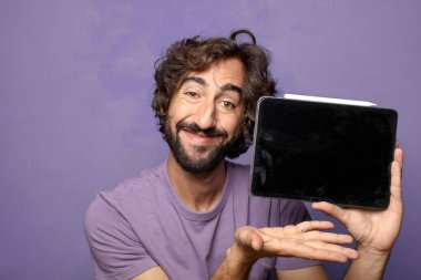 Genç, sakallı, dokunmatik ekranı tutan bir adam.