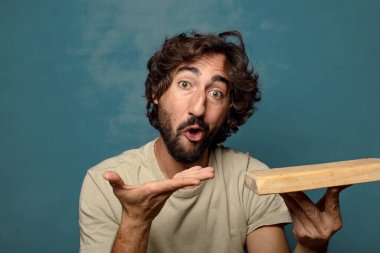 Boş tahta kesim masası olan genç, sakallı bir adam.