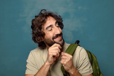 Çantası olan genç, sakallı bir adam.