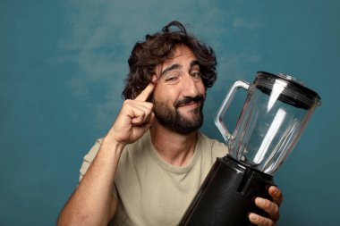 Genç, sakallı, blender makineli bir adam.