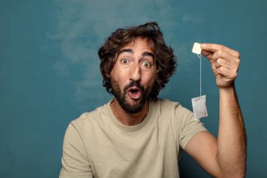 Genç, sakallı, çay içen bir adam.