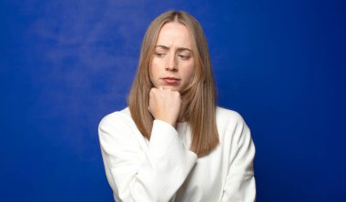 Ciddi, düşünceli ve endişeli hissediyorum. Elleri çenesine değmiş şekilde yan yan bakıyor.