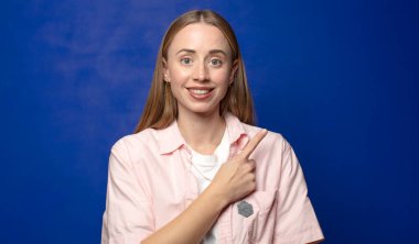 Neşeli bir şekilde gülümseyen, mutlu hisseden, kenarı ve yukarıyı gösteren, kopya uzayda nesneleri gösteren