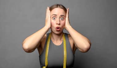 Heyecanlı ve şaşırmış görünüyor, ağzı açık, elleri başının üstünde, şanslı bir kazanan gibi hissediyor. fitness konsepti