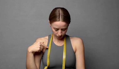 Neşeli bir şekilde ve gelişigüzel gülümsüyor, aşağıya bakıyor ve göğsüne işaret ediyor. fitness konsepti