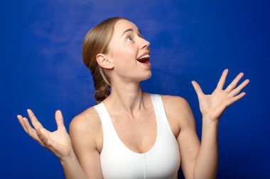 Sarışın kadın kendini mutlu, şaşkın, şanslı ve şaşırmış hissediyor. Zaferi kutlarken iki eli havada.