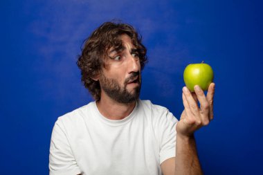 Elma tutan genç, sakallı adam.