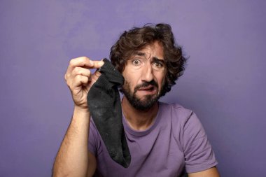 Kirli çorabı olan genç, sakallı bir adam.