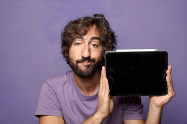 Genç, sakallı, dokunmatik ekranı tutan bir adam.