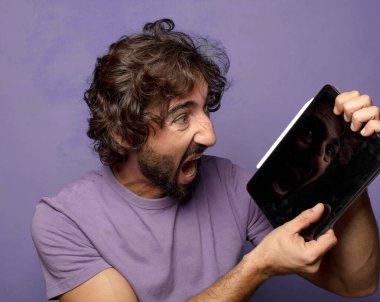 Genç, sakallı, dokunmatik ekranı tutan bir adam.