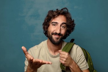 Çantası olan genç, sakallı bir adam.