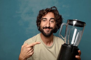 Genç, sakallı, blender makineli bir adam.