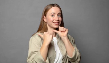 Neşeli bir şekilde gülümsüyor ve yan taraftaki fotokopi alanını işaret ediyor, mutlu ve tatmin olmuş hissediyordu.