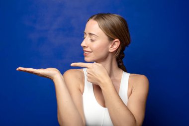 Sarışın kadın gülümsüyor, mutlu, kaygısız ve tatmin olmuş hissediyor, fotokopi alanındaki konsepte ya da fikre işaret ediyor.