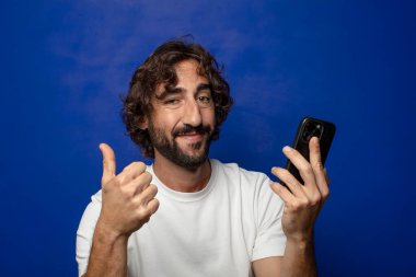 Akıllı telefonu olan genç, sakallı bir adam.
