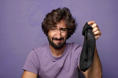 Kirli çorabı olan genç, sakallı bir adam.