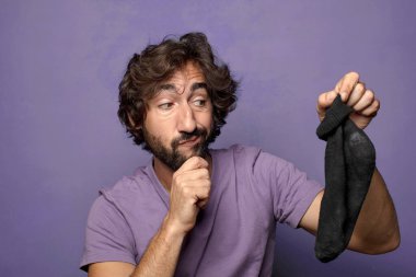 Kirli çorabı olan genç, sakallı bir adam.