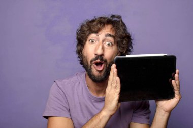 Genç, sakallı, dokunmatik ekranı tutan bir adam.