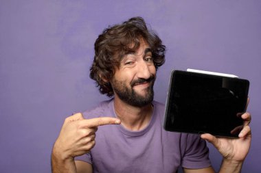 Genç, sakallı, dokunmatik ekranı tutan bir adam.