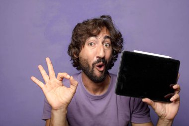 Genç, sakallı, dokunmatik ekranı tutan bir adam.