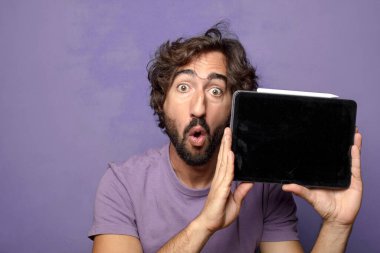 Genç, sakallı, dokunmatik ekranı tutan bir adam.