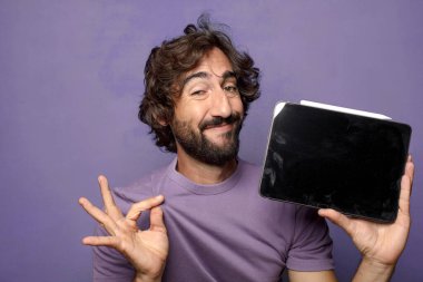 Genç, sakallı, dokunmatik ekranı tutan bir adam.