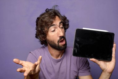 Genç, sakallı, dokunmatik ekranı tutan bir adam.