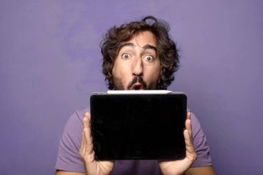 Genç, sakallı, dokunmatik ekranı tutan bir adam.