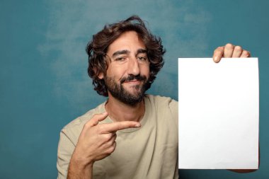 Genç, sakallı, elinde kağıt olan bir adam.