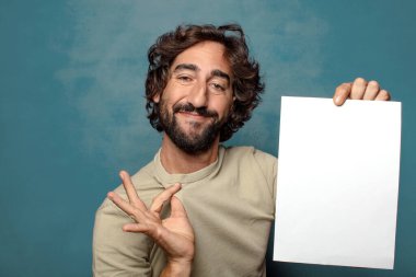 Genç, sakallı, elinde kağıt olan bir adam.
