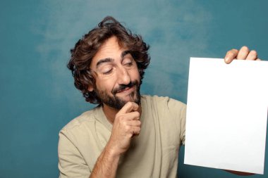 Genç, sakallı, elinde kağıt olan bir adam.