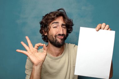 Genç, sakallı, elinde kağıt olan bir adam.