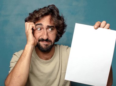 Genç, sakallı, elinde kağıt olan bir adam.