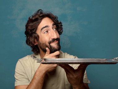 Gümüş tepsisi olan genç, sakallı bir adam.