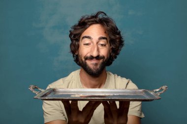 Gümüş tepsisi olan genç, sakallı bir adam.