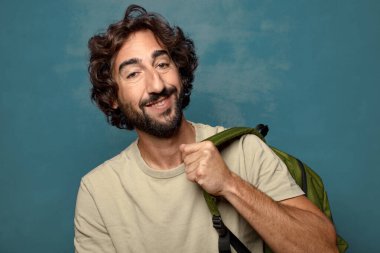 Çantası olan genç, sakallı bir adam.