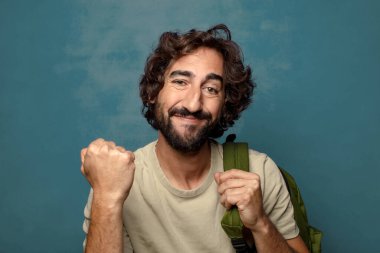 Çantası olan genç, sakallı bir adam.