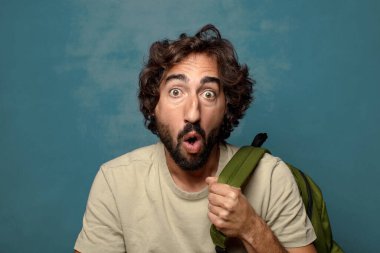 Çantası olan genç, sakallı bir adam.