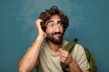 Çantası olan genç, sakallı bir adam.