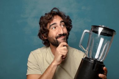 Genç, sakallı, blender makineli bir adam.