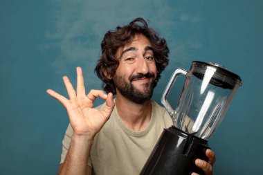 Genç, sakallı, blender makineli bir adam.