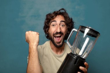 Genç, sakallı, blender makineli bir adam.