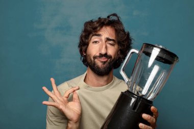 Genç, sakallı, blender makineli bir adam.