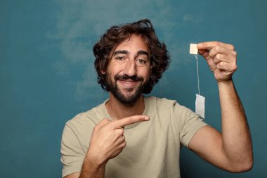 Genç, sakallı, çay içen bir adam.