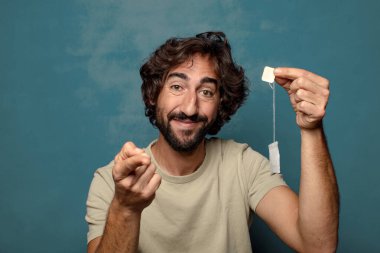 Genç, sakallı, çay içen bir adam.