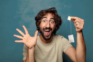 Genç, sakallı, çay içen bir adam.