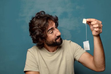 Genç, sakallı, çay içen bir adam.