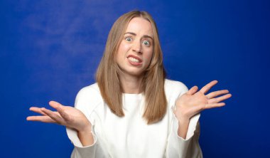 Şaşırmış, kafası karışmış ve stresli görünüyor, farklı seçenekler arasında merak ediyor, kararsız hissediyor.