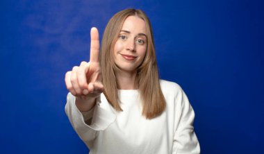 Gururla ve kendinden emin bir şekilde gülümseyerek bir numaralı pozu vererek, bir lider gibi hissederek.