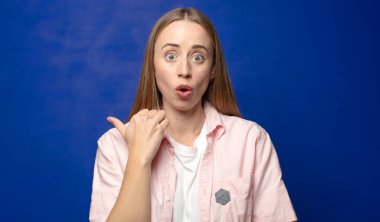 İnançsızlıktan şaşkın şaşkın bakıyor, yan taraftaki objeyi işaret ediyor ve 